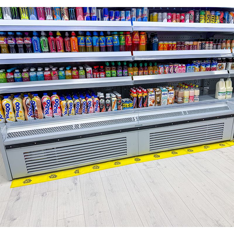 Bande absorbante eau PIG® Essentials installée devant un meuble frigorifique de supermarché